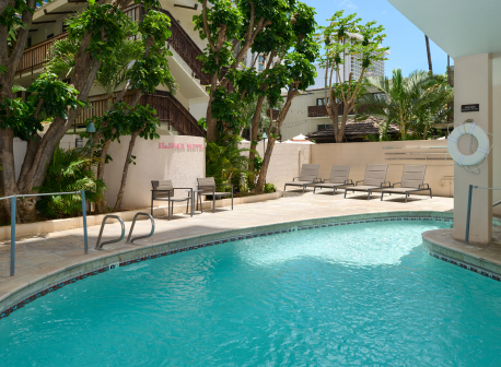 A clear blue swimming pool surrounded by a sunlit patio.
